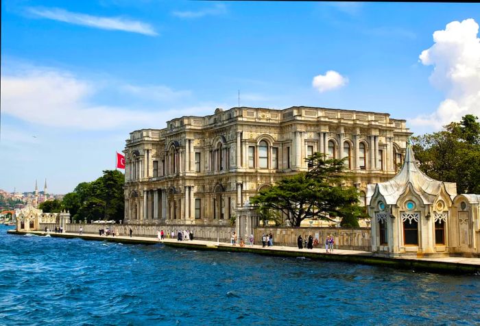 Pedestrians stroll along the promenade outside a palace by the Bosporus in Istanbul.