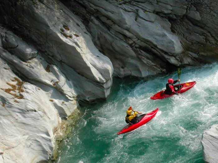 Two kayakers navigating through swift waters