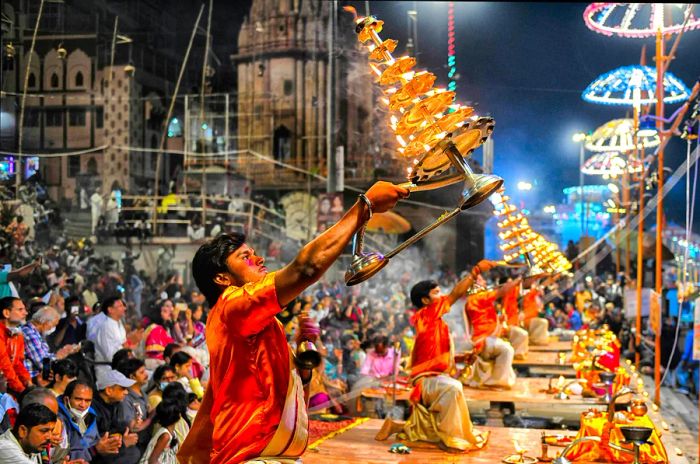 Hindu priests conduct evening prayers surrounded by flickering candles.