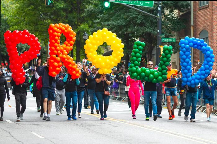 Individuals carry oversized balloon letters that form