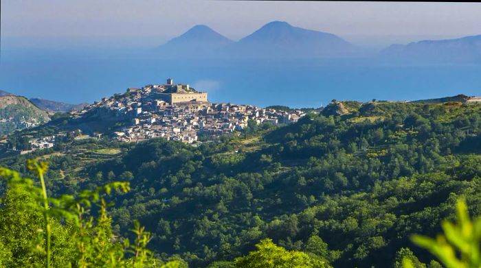 A medieval hill town enveloped by woodlands and distant mountain ranges