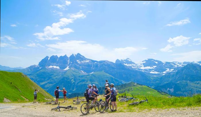 Mountain bikers pause at a scenic viewpoint overlooking the Swiss Alps in the Portes du Soleil area.