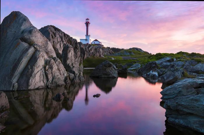 A lighthouse perched on rocky cliffs at sunrise