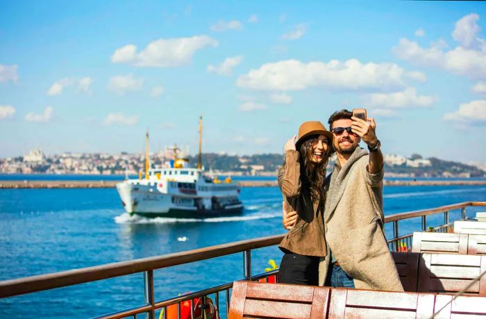 A couple smiles for a selfie on the ferry, with the stunning Istanbul skyline in the background.