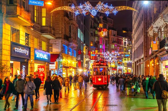 Pedestrians strolling along Istiklal Street in Beyoğlu, Istanbul, with a tram running through the center.