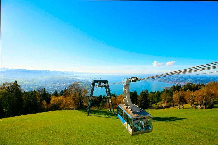 A cable car ascends with the magnificent Lake Constance as a backdrop.