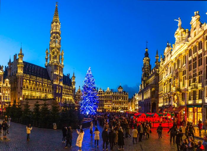 A beautifully lit Christmas tree adorns a bustling city square.