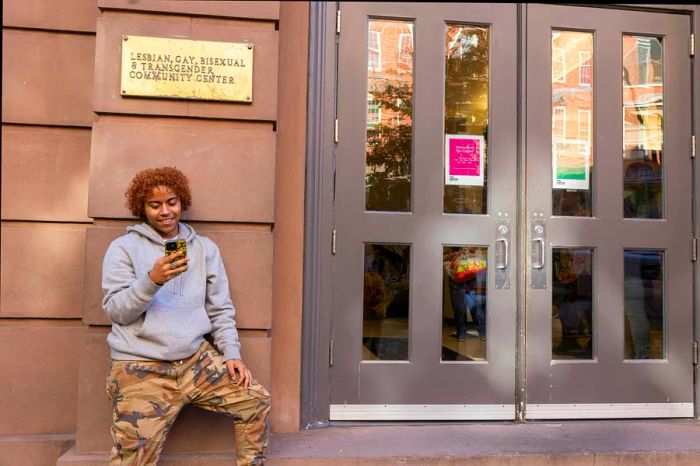 A person checks their phone at the entrance of The Lesbian, Gay, Bisexual & Transgender Community Center, West Village, New York City, New York, USA