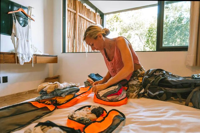 A woman is organizing her clothes into separate packing cubes.