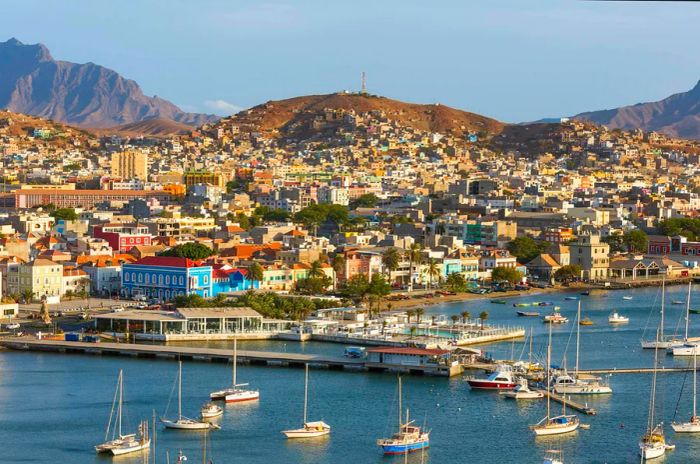 A bustling port city with small boats anchored offshore