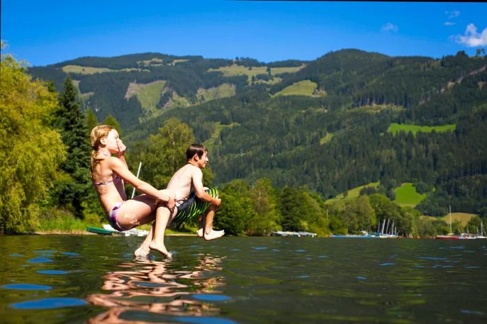 Two young children leaping into Lake Zell on a summer day