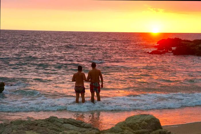 Two men enjoy the surf at sunset on Conchas Chinas beach in Puerto Vallarta, Jalisco, Mexico