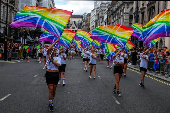 Marchers wave rainbow flags layered with the Union Jack during the Pride parade in London, England, United Kingdom