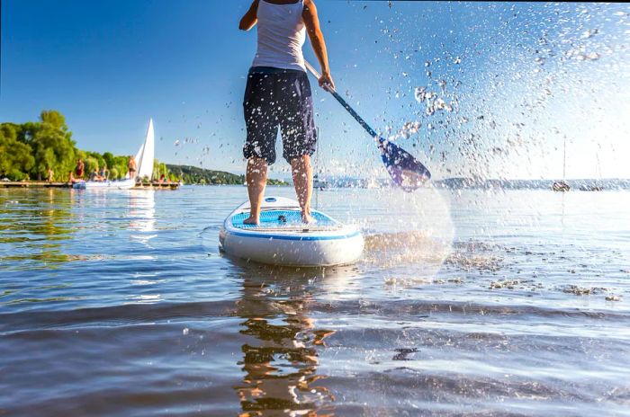 A scenic view of a person paddleboarding on a lake from behind