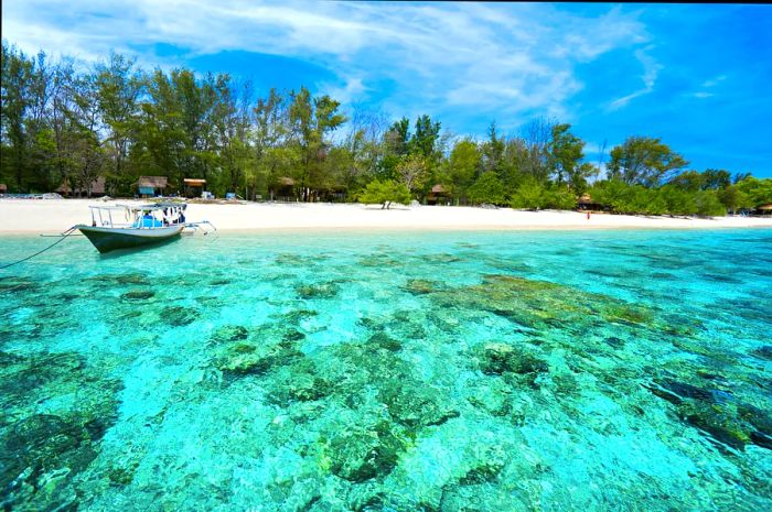 A boat rests by the sandy shore in crystal-clear turquoise waters