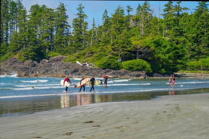 Surfers stroll along the beach, boards in hand, leaving the waves behind.