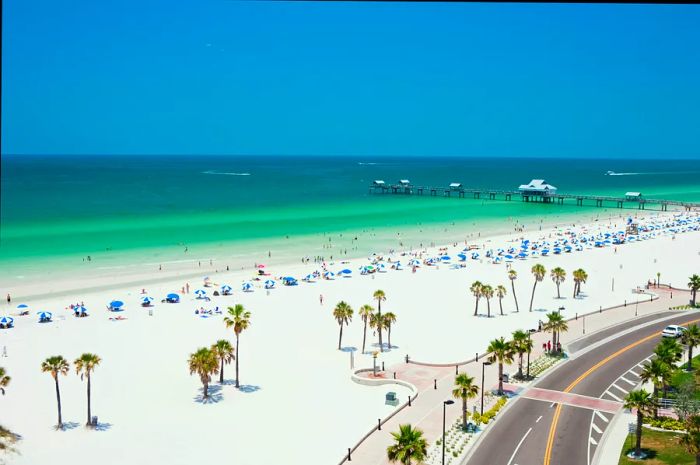 An aerial shot capturing people relaxing on a white sand beach with stunning turquoise waters at Florida's Clearwater Beach