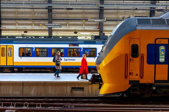 Amsterdam Centraal train station bustling with travelers and NS Intercity trains at the main hub