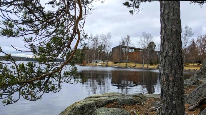 The exterior of a contemporary building set in expansive grounds near a lake