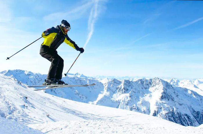 A skier leaping against a backdrop of towering alpine peaks