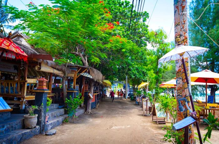 Visitors stroll along a pathway lined with shops and restaurants near the beach