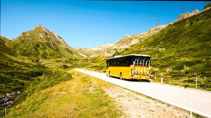 A yellow PostBus traversing the Nufenen Pass between Ticino and Valais, Switzerland