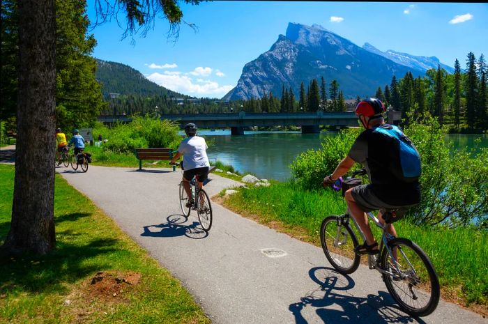 Cyclists enjoy a scenic riverside path on a sunny day.