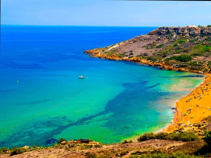 A sandy bay with orange hues meeting a turquoise ocean