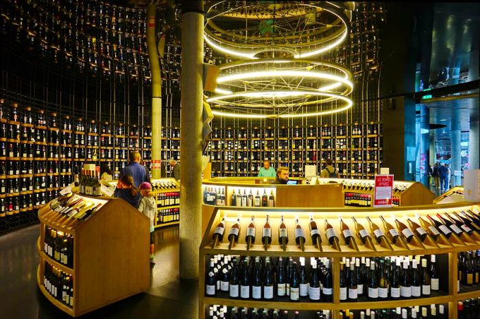 Floor-to-ceiling shelves showcase hundreds of wine bottles available for purchase at La Cité du Vin wine museum.