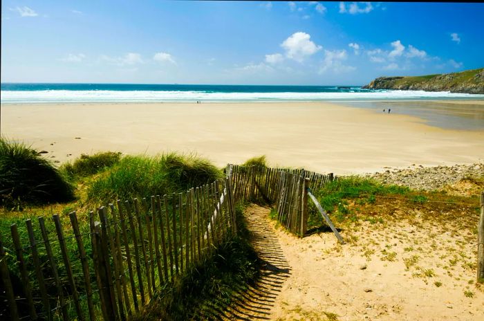 A pristine sandy beach with a few walkers on the northern coast of France.