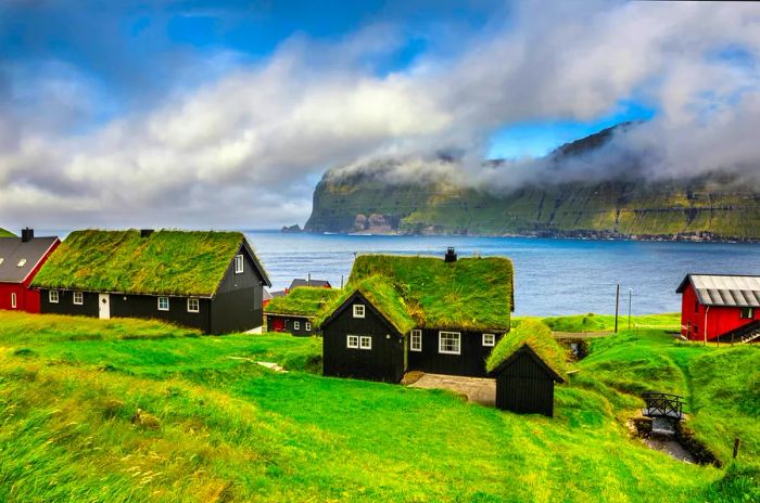 Houses with grass-covered roofs are set against the lush backdrop of the Faroe Islands.