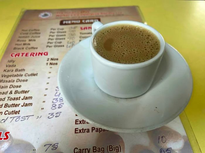 A cup of filter coffee with a saucer resting on a menu