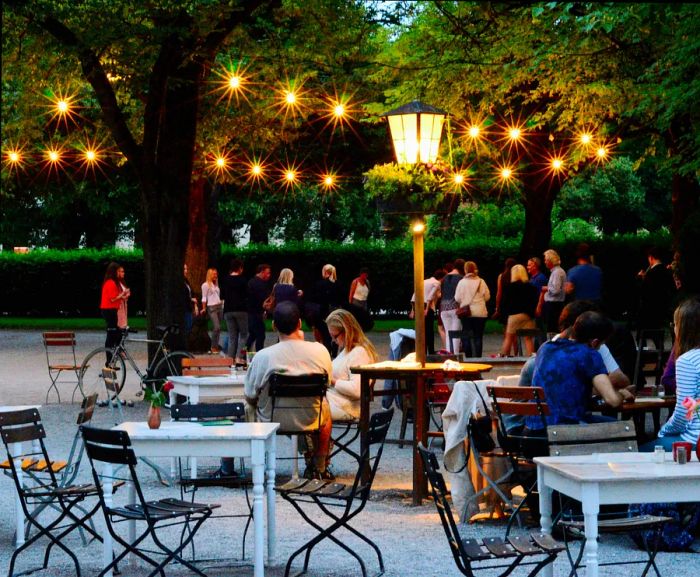 People enjoy drinks at an outdoor café in Munich during the evening.