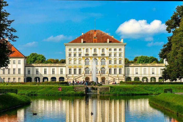 The impressive facade of a sprawling palace with visitors strolling on its terraces