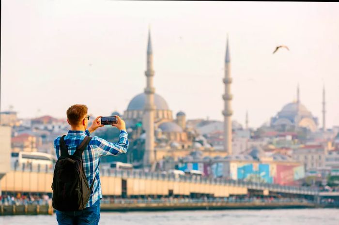 A man captures a photo of Hagia Sophia from a scenic viewpoint.