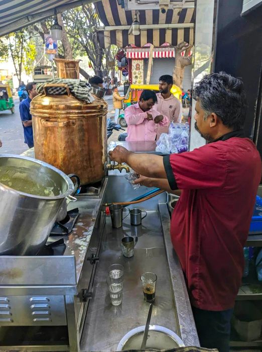 A street vendor prepares coffee using a large urn