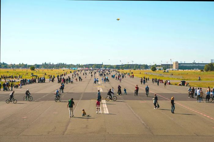 Pedestrians and cyclists enjoy the former runway of the now-abandoned Tempelhofer Feld airport in Berlin, Germany