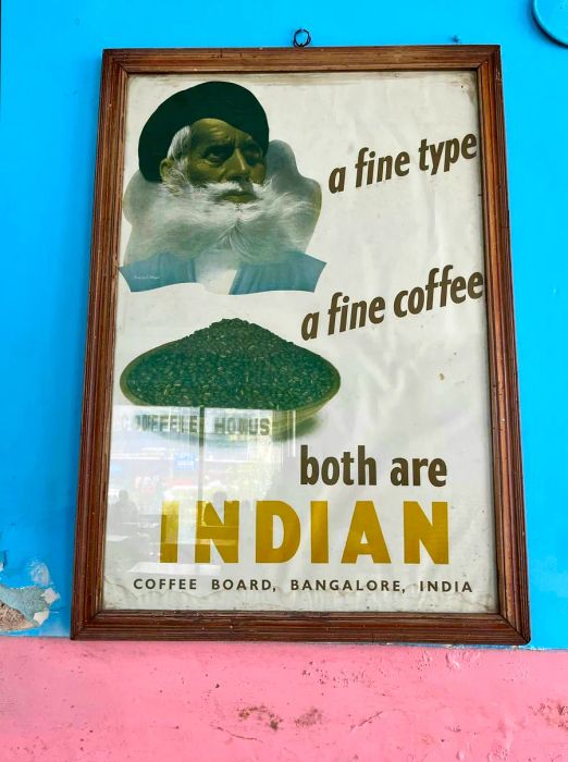 A framed poster promoting Indian coffee displayed on the walls of a coffee house