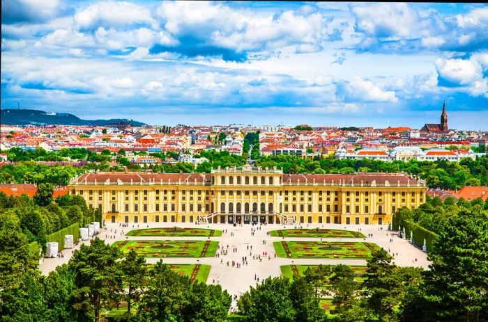 An aerial view of a palace courtyard bustling with people on the lawns