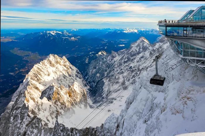 A cable car station perched atop a mountain offers stunning views of distant snowy peaks.