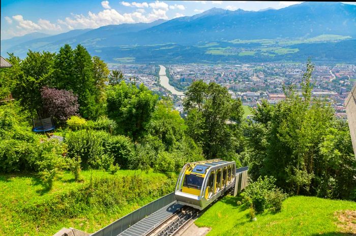 A yellow mountain railway carriage ascends a steep slope.