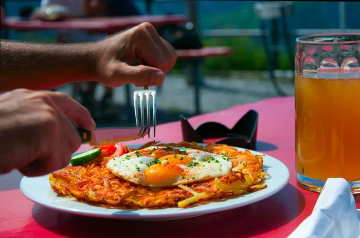 A man enjoying rösti at a sunlit table