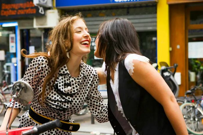 A woman on a scooter embracing a friend.