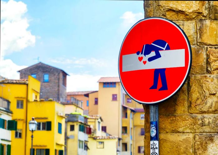 A circular no entry sign has been creatively modified by a street artist to feature a cartoon police officer.