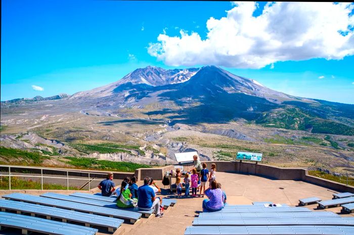 A park ranger addresses visitors against a backdrop of a volcanic landscape