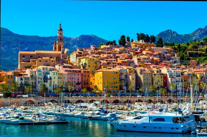 A stunning church and pastel-colored buildings grace a hill overlooking a marina filled with boats