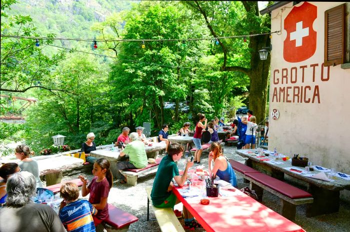 Diners enjoying a meal in the garden of a grotto restaurant in Ticino, Switzerland