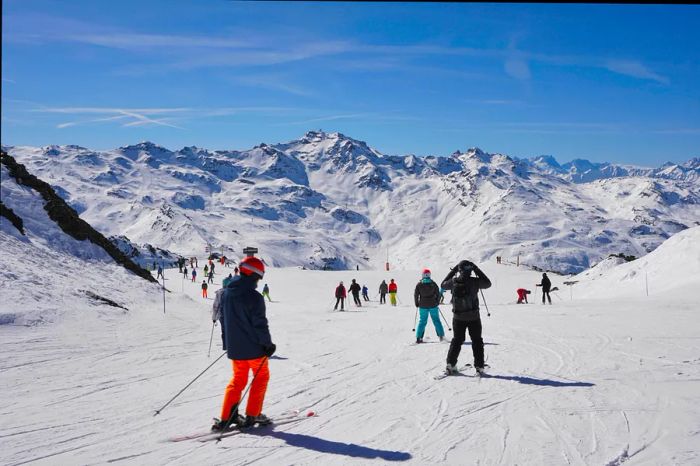 A bustling scene of skiers enjoying a sunny day on the slopes at Les Menuires in the Trois Vallées region of France