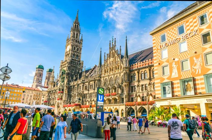 A bustling crowd strolling through a town square, framed by an impressive Gothic building