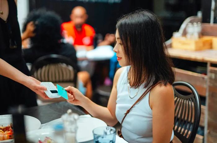 A woman swipes her credit card at a restaurant